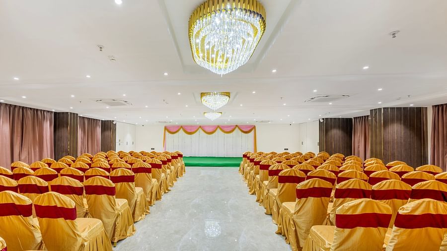 Lemonridge Hotels, KPHB | Banquet hall with rows of chairs arranged, facing a stage. Ready for a gathering.